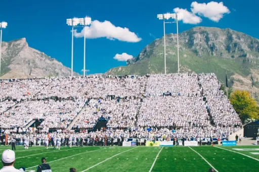 Estádio de futebol americano com bancadas cheias de espectadores e montanhas ao fundo.