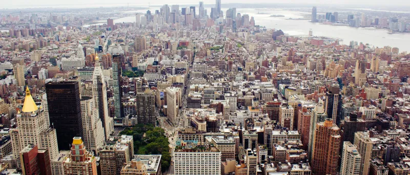 Vista aérea de Manhattan, em Nova Iorque, com numerosos edifícios e o One World Trade Center ao fundo.